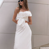 Three-quarter close-up view of an off-white strapless crop top highlighting the large sculptural front knot bow.