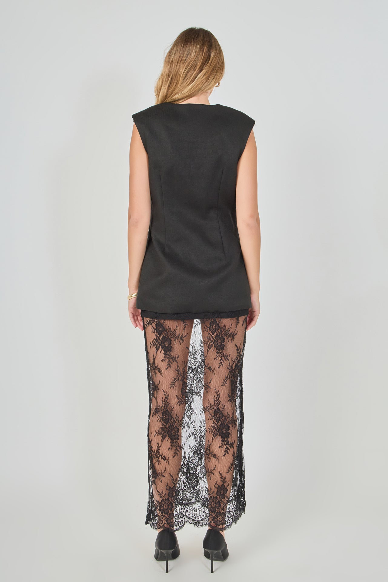 Back view of black tailored vest lace maxi dress featuring a sleeveless tailored vest back and a sheer floral lace skirt.