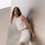 Side profile view of an off-white sleeveless crop top showcasing the relaxed boxy silhouette and armhole cut.