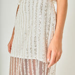 Ultra close-up detail view of off-white sheer mesh fabric detailing shimmering vertical sequin stripes and an invisible side zipper seam.