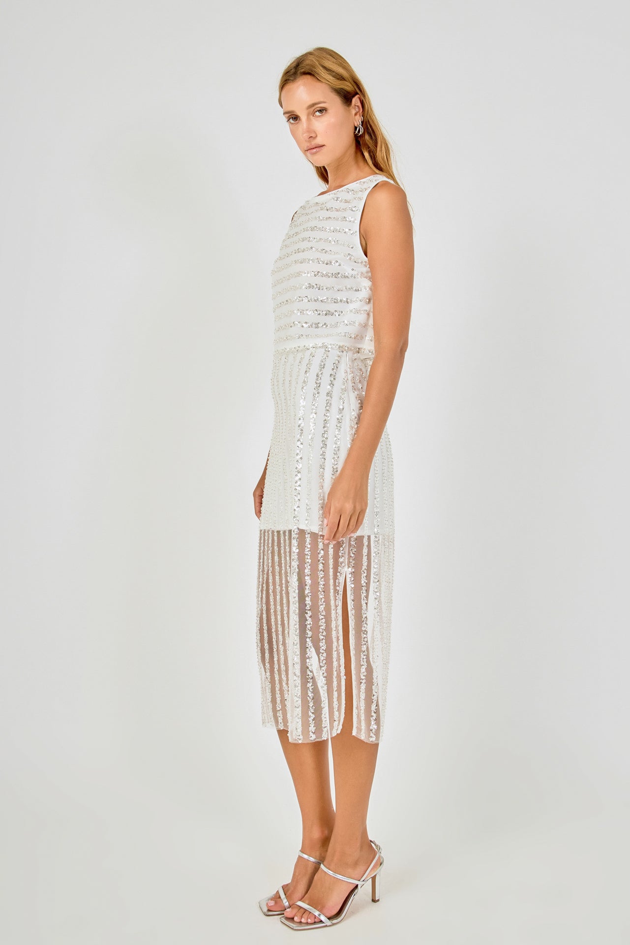 Side view of off-white sequin stripe mesh midi skirt featuring a straight midi profile and sheer mesh skirt lining.