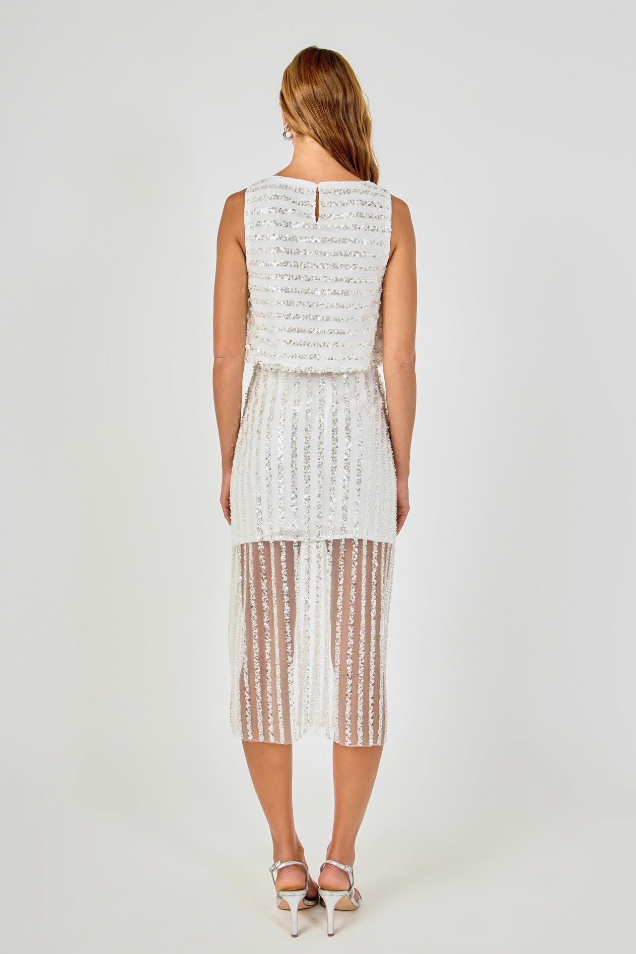 Back view of off-white sequin stripe mesh midi skirt featuring a straight waistline, vertical sequin stripes, and a sheer mesh hem.