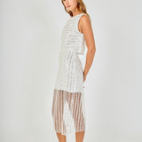 Side posed view of an off-white sequin stripe mesh midi skirt featuring an opaque mini skirt lining and sheer hem, styled with a matching sequin crop top.