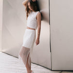 Full-length side profile view of an off-white high-waisted midi skirt featuring vertical sequin stripes, an opaque mini lining, a sheer lower hem, and a side slit.