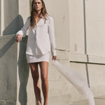 Full-length outdoor view of an ivory sequined mini skirt featuring a lattice sequin pattern, styled with an embellished long-sleeve blouse.