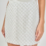 Close-up view of white pearl embellished mini skirt highlighting the H-line silhouette and pearl lattice detailing from waist to hem.