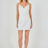 Full-length front view of a white H-line mini skirt with all-over pearl lattice embellishments, paired with a white satin cowl-neck top.