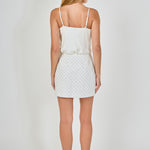 Back view of white pearl embellished mini skirt showing the straight waistline and continuous lattice pearl embroidery.