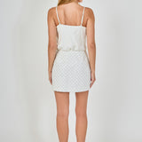 Back view of white pearl embellished mini skirt showing the straight waistline and continuous lattice pearl embroidery.