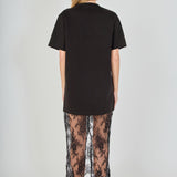 Back view of black mix media maxi dress featuring a short-sleeve t-shirt bodice, sheer floral lace skirt, and a back slit.