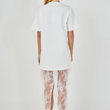 Back view of white mix media maxi dress featuring a short-sleeve t-shirt bodice, sheer floral lace skirt, and a back slit.