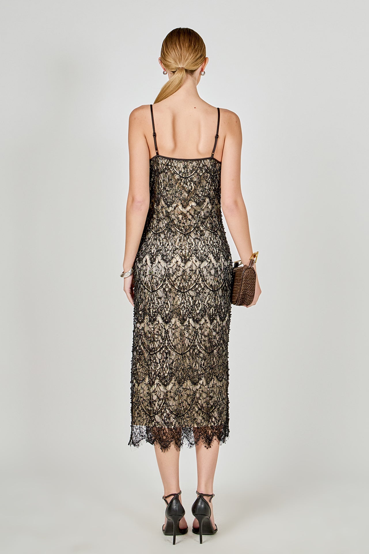 Back view of black beaded lace midi dress featuring thin spaghetti straps, a low scoop back, and a straight hemline.