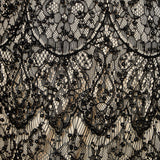 Detail view of black lace fabric featuring intricate scalloped embroidery, black bead embellishments, and a contrast nude lining.
