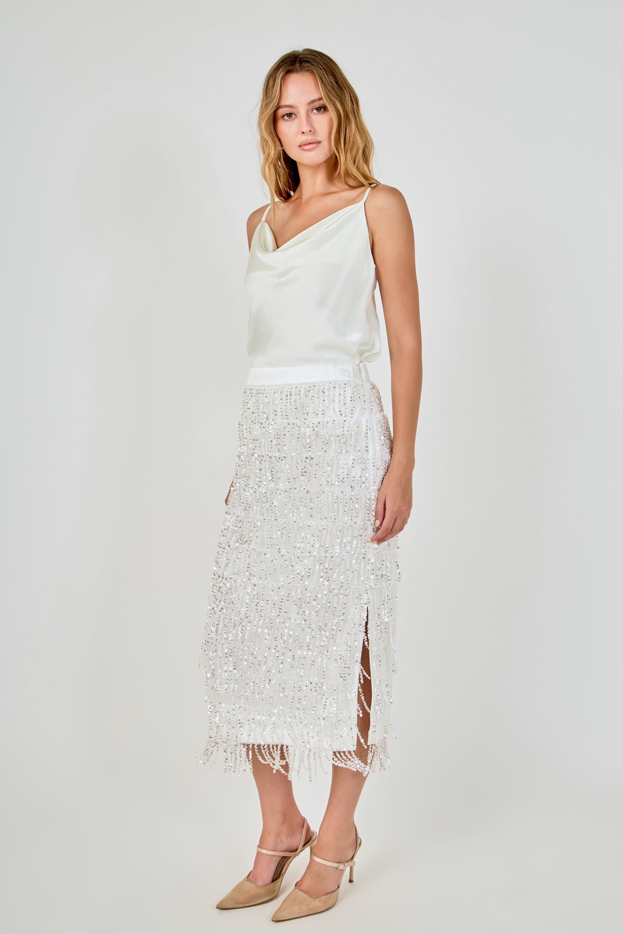 Side view of white high-waisted sequin fringe midi skirt featuring a straight profile and subtle side seam.