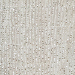 Ultra close-up detail view of white mesh fabric densely embroidered with tiered rows of shimmering metallic sequin fringe.
