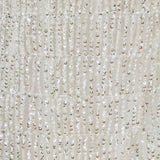 Ultra close-up detail view of white mesh fabric densely embroidered with tiered rows of shimmering metallic sequin fringe.