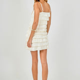 Back view of cream tiered bubble mini dress showing the straight rear neckline, thin straps, and full-length layered tiers.