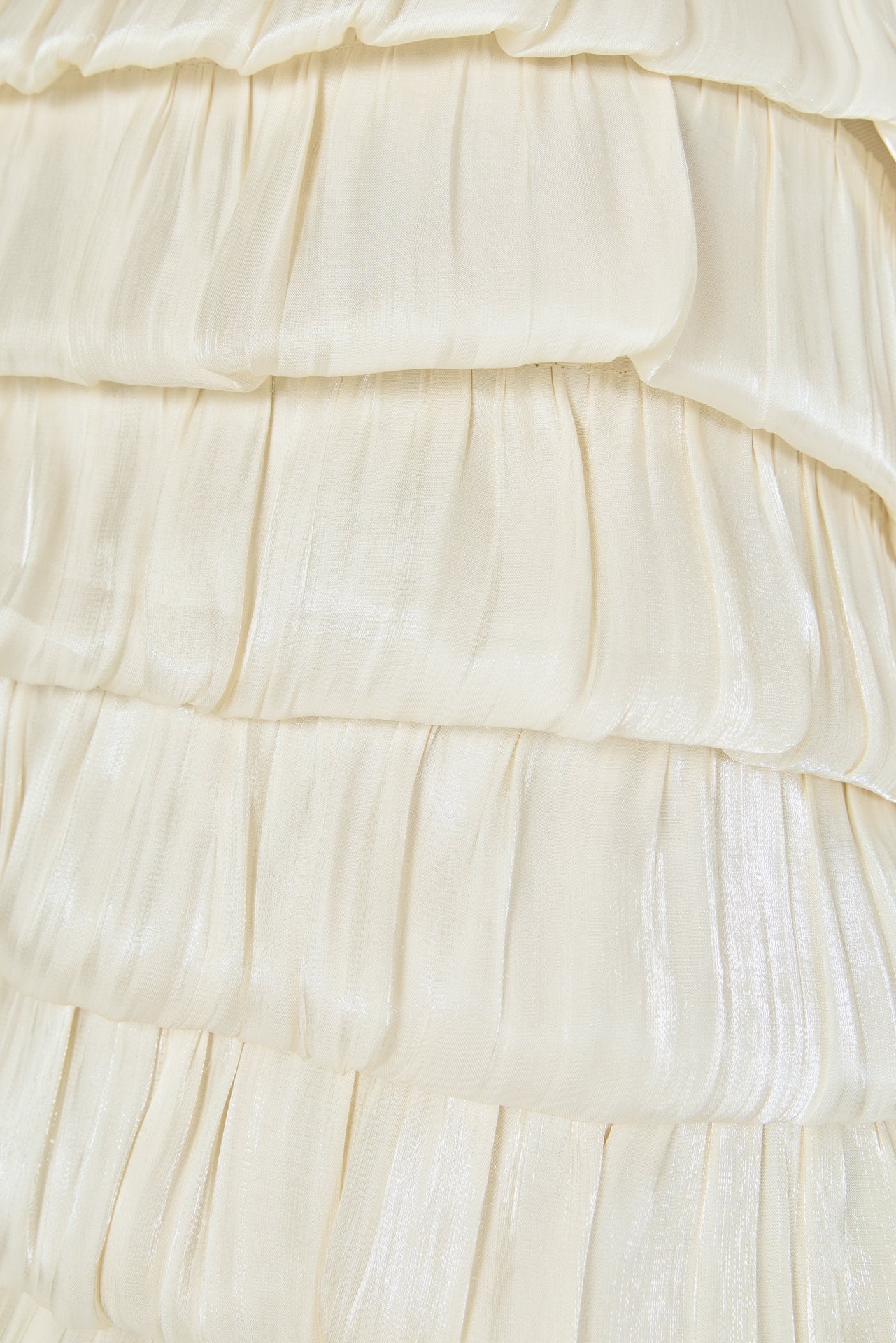 Ultra close-up detail view of cream pleated fabric arranged in textured, overlapping ruffled bubble tiers.