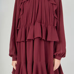 Zoomed-in view focusing on the chest, detailing the smocked high collar, the sheer fabric of the bishop sleeves, and the complex vertical cascading ruffles that frame the bodice.
