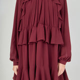 Zoomed-in view focusing on the chest, detailing the smocked high collar, the sheer fabric of the bishop sleeves, and the complex vertical cascading ruffles that frame the bodice.