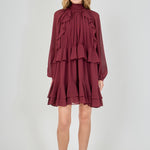 Full-length front view of a deep burgundy chiffon mini dress, featuring a smocked high neck, voluminous bishop sleeves, and a cascading tiered ruffled skirt.