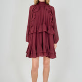 Full-length front view of a deep burgundy chiffon mini dress, featuring a smocked high neck, voluminous bishop sleeves, and a cascading tiered ruffled skirt.