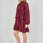 Profile view of the burgundy chiffon mini dress, showcasing the side silhouette, the fullness of the sheer balloon sleeves, and how the layers of the tiered ruffled skirt drape from the side.