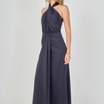 Side view of navy draped halter maxi dress featuring a high halter neckline, front drape detail, and a fluid maxi skirt.