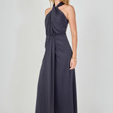 Side view of navy draped halter maxi dress featuring a high halter neckline, front drape detail, and a fluid maxi skirt.