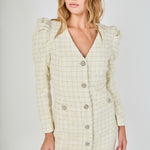 Face-forward posed view of an ivory long-sleeve tweed blazer mini dress featuring a deep V-neckline, structured puff shoulders, and crystal button closures.