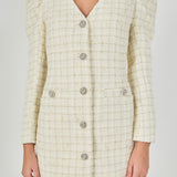 Upper bodice close-up view of an ivory windowpane tweed mini dress highlighting the V-neckline, puffed sleeve caps, and decorative crystal buttons.
