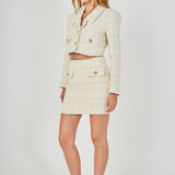 Side profile view of an ivory high-waisted tweed mini skirt and cropped jacket set showing the fitted mini silhouette.