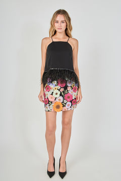 Black floral embroidered mini skirt featuring vibrant multi-colored flower embroidery, a high waist, and a straight hem, styled with a black feather-trimmed camisole top.