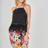Black floral embroidered mini skirt featuring vibrant multi-colored flower embroidery, a high waist, and a straight hem, styled with a black feather-trimmed camisole top.