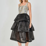 Side view of a mixed-media midi dress featuring a fitted floral jacquard bodice and a voluminous black tiered organza skirt.