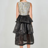 Back view of a mixed-media midi dress featuring a square back neckline, fitted floral jacquard bodice, and a three-tiered black organza midi skirt.