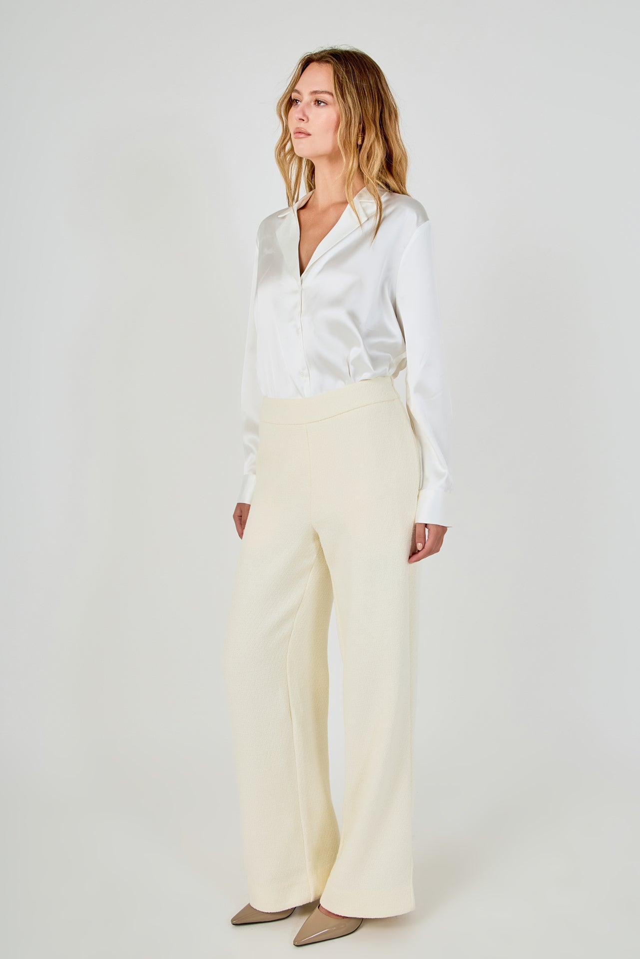 Side profile view of cream high-waisted wide-leg tweed trousers showcasing the relaxed leg fit and floor-length hem.