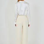Straight-on back view of cream high-waisted wide-leg tweed trousers showing rear welt pocket details and clean drape.