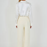 Straight-on back view of cream high-waisted wide-leg tweed trousers showing rear welt pocket details and clean drape.