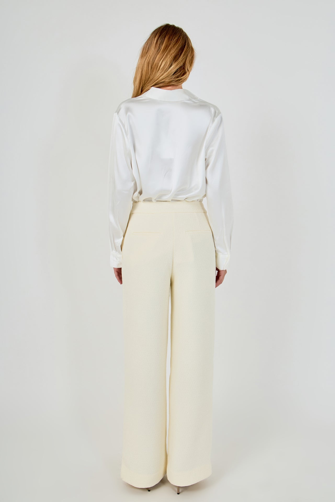 Straight-on back view of cream high-waisted wide-leg tweed trousers showing rear welt pocket details and clean drape.