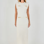 Full-length front view of a cream sleeveless knit maxi dress showing the complete column fit and front decorative gold pocket accents.
