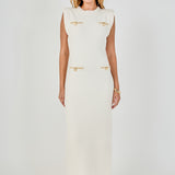 Full-length front view of a cream sleeveless knit maxi dress showing the complete column fit and front decorative gold pocket accents.