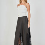 Side view of black maxi skirt featuring an A-line silhouette with sheer black lace inserts at the hem.
