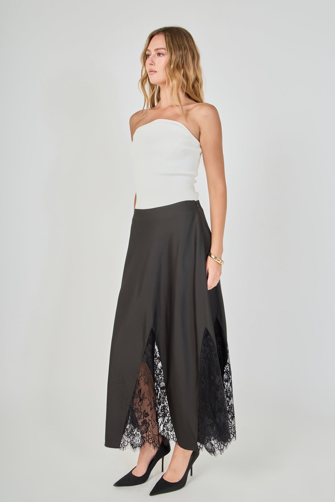 Side view of black maxi skirt featuring an A-line silhouette with sheer black lace inserts at the hem.