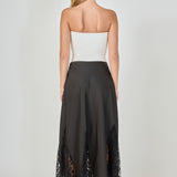 Back view of black maxi skirt featuring a smooth high waistband and sheer black lace godet panels along the hemline.