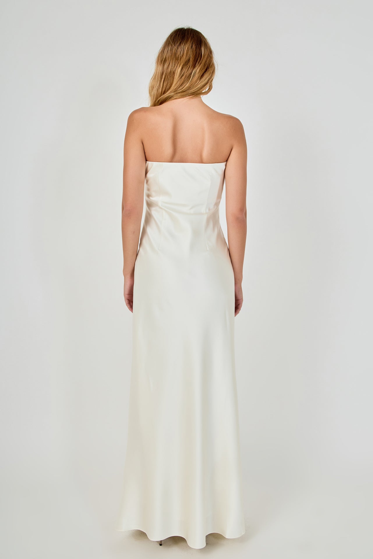 Straight-on rear view of an ivory strapless satin maxi dress displaying the straight back neckline, structured back seams, and fluid skirt fall.
