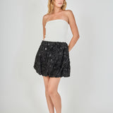 Detail view of the black skirt fabric showcasing dense 3D floral rosettes layered with shimmering black sequins.