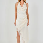 Full-length front view of a champagne satin halter dress with a draped cowl neckline, asymmetrical skirt drape, and eyelash lace trim.