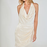 Face-forward posed view of a champagne satin halter cowl-neck dress with asymmetrical eyelash lace detailing.