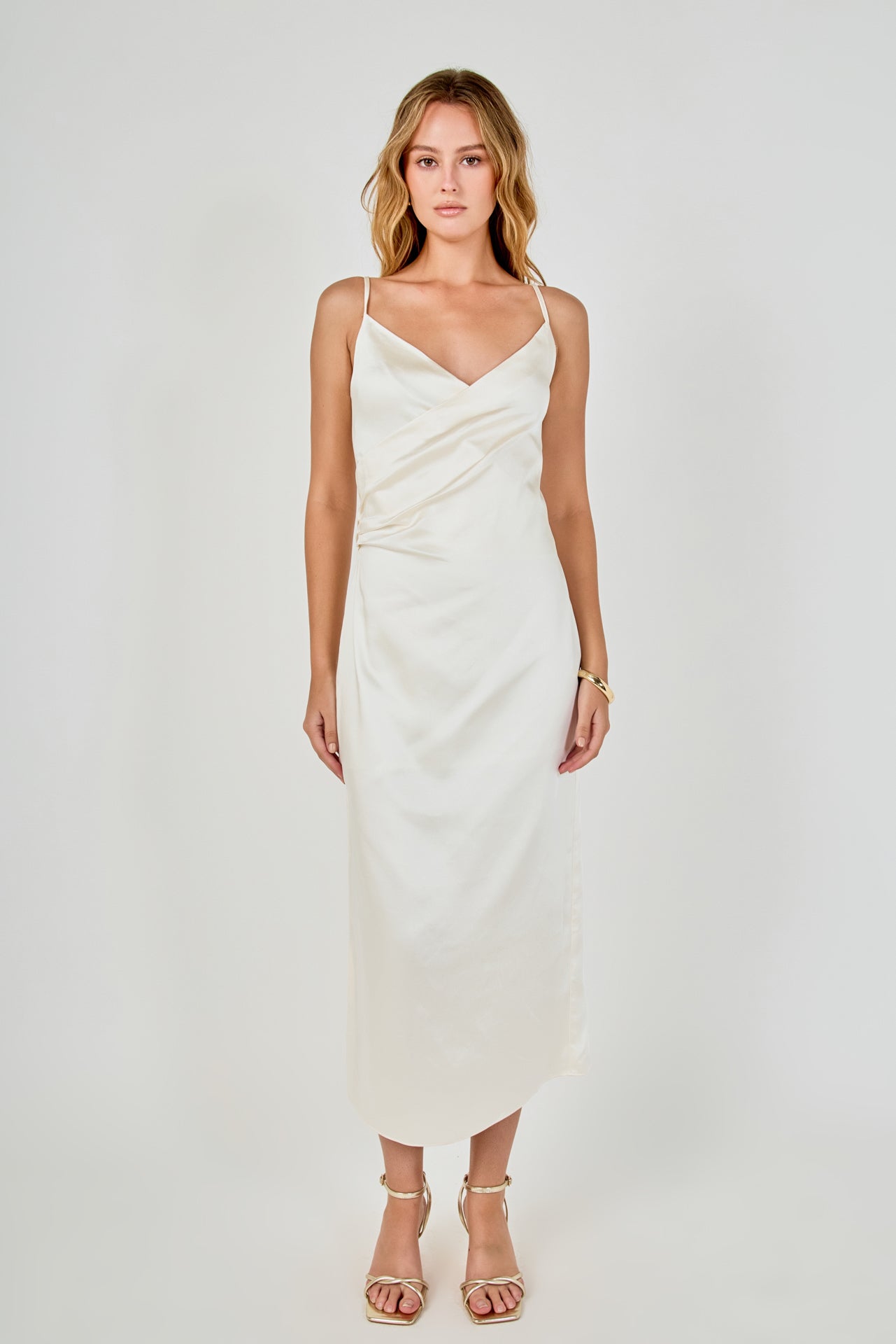 Full-length front view of a champagne satin wrap midi dress showcasing the wrap neckline, ruched waist detail, and straight skirt silhouette.